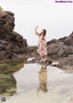 A woman standing on a rock in the water.